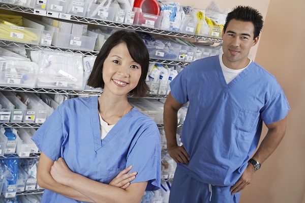 Female and male nurse standing by shelves with medical supply, portrait